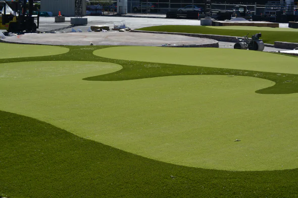 Professional artificial turf installation featuring custom-designed synthetic putting greens with contoured edges, installed for a commercial golf and entertainment space.